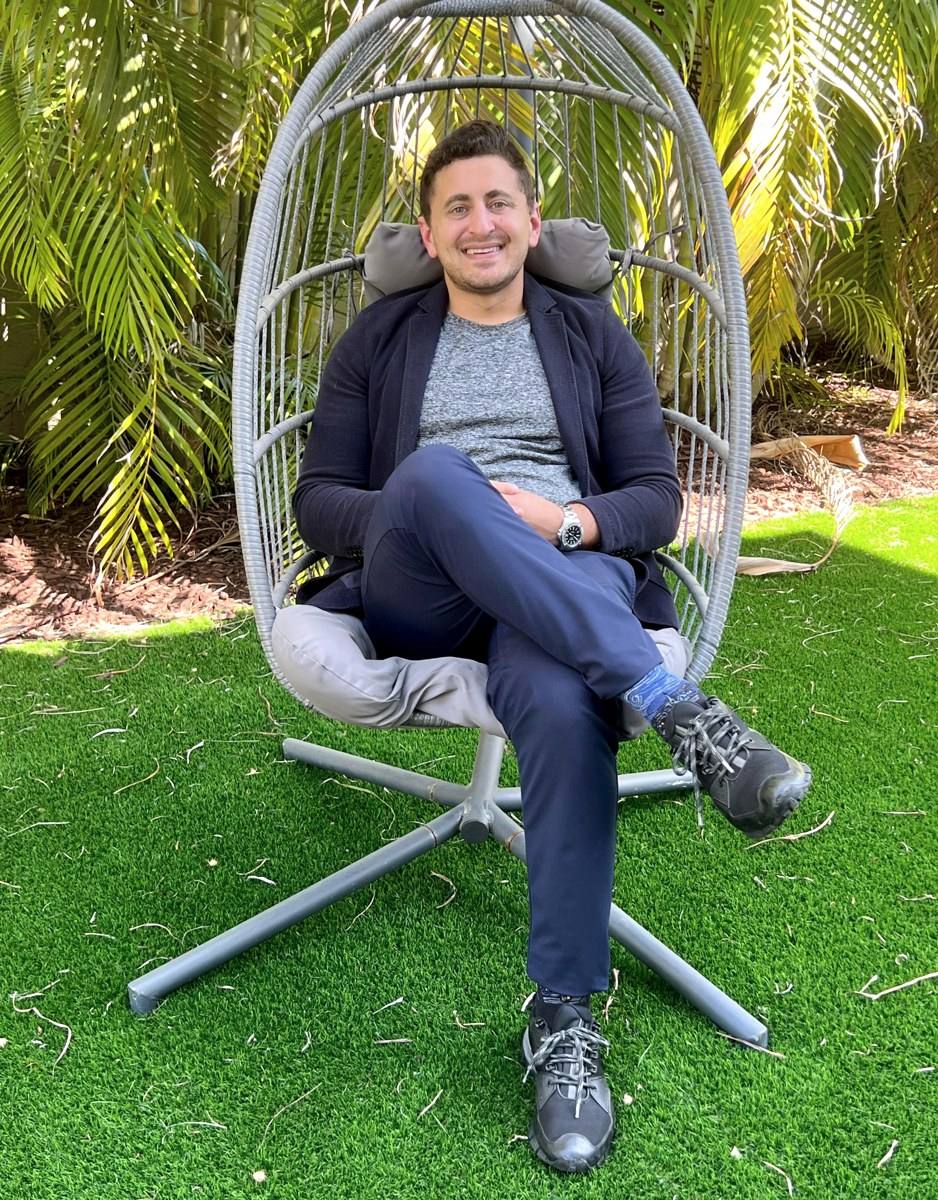 Michael Neuman seated outdoors among palms